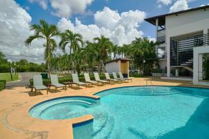 a swimming pool with lounge chairs and a building at Hideaway in Paradise in Juan Dolio