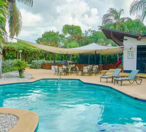 a swimming pool with a patio with tables and chairs at Hideaway in Paradise in Juan Dolio