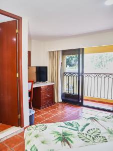a bedroom with a bed and a desk and a balcony at Hotel del Gobernador in Mérida