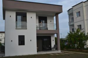 a white house with a balcony in front of two buildings at Vila 18 in Velipojë