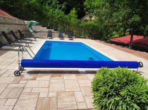 a blue swimming pool with chairs in a yard at Къща за гости ДАЯНИЦА in Kopilovtsi