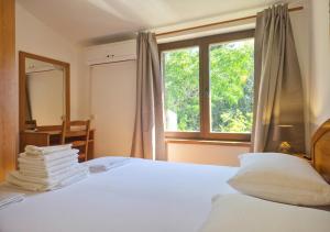 a bedroom with a white bed with a window at Apartments Mrva in Ugljan