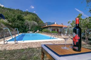a bottle of wine sitting on a table next to a wine glass at Villa Supina - 3BDR with Pool & Panoramic Lake Garda Views in Toscolano Maderno