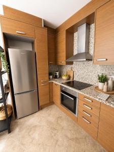 a kitchen with wooden cabinets and a stainless steel refrigerator at LAttic Reserva BiosferaTerres de lEbre in Sant Carles de la Ràpita