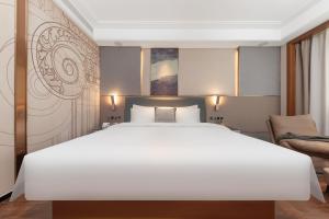 a bedroom with a large white bed and a couch at ChillNow Hotel Guangzhou in Guangzhou