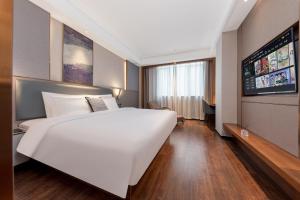 a large white bed in a room with a flat screen tv at ChillNow Hotel Guangzhou in Guangzhou