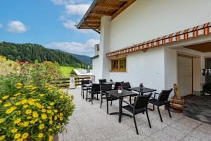 a patio with black tables and chairs and flowers at Haus Enzian in Thiersee +26 photos