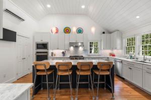 a kitchen with white cabinets and a kitchen island with stools at Heated Plunge Pool Theater Room Backyard Fun in Orleans