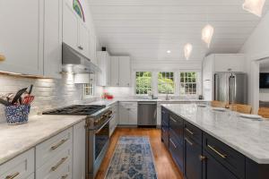 a kitchen with white cabinets and a blue island at Heated Plunge Pool Theater Room Backyard Fun in Orleans