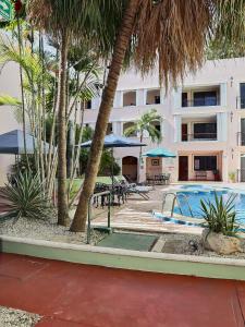 a hotel with a pool and tables and palm trees at Hotel del Gobernador in Mérida