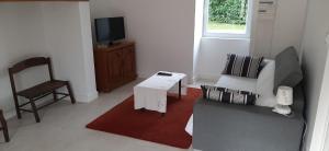 a living room with a couch and a tv and a chair at Gîte de campagne au cœur du Périgord à Rouffignac-Saint-Cernin-de-Reilhac in Rouffignac Saint-Cernin
