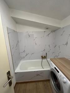 a bathroom with a white tub and a washing machine at Appartement Duplex Mezzanine Station Ski Valberg in Péone