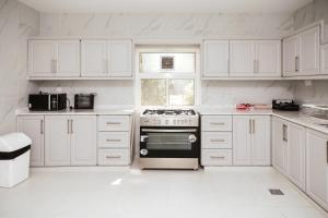eine weiße Küche mit weißen Schränken und einem Backofen in der Unterkunft ALSARA HiDEAWAY in Qūr