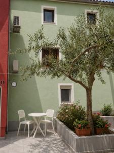 a table and chairs in front of a green building at Apartma Oliva in Koper