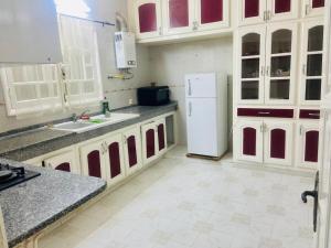 a kitchen with white cabinets and a white refrigerator at Appart AL MARAII - Familles seulement in Beni Khiar +7 photos