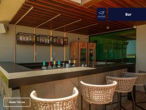 a bar with wicker chairs at a bar with a bar assistant at Marino Beach Hotel in Cabo Frio