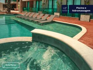 a swimming pool with lounge chairs in a building at Marino Beach Hotel in Cabo Frio