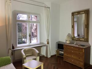 a living room with a chair a dresser and a window at Lilienthalschlösschen in Berlin