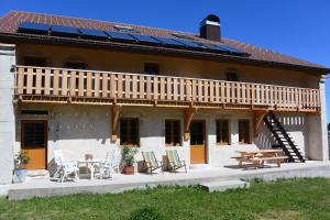 a house with a deck and a table and chairs at Gîtes Tré Le Grenier in Les Moussières