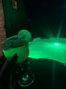a person holding a green drink with a lime garnishment at Chalé estrela de ouro in Alexânia