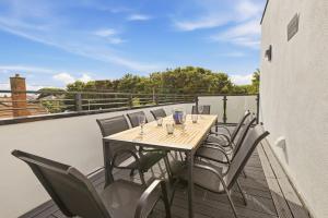 a wooden table and chairs on a balcony at Beadnell Point - North East Escapes in Beadnell