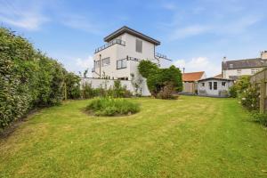a large yard with a white house at Beadnell Point - North East Escapes in Beadnell