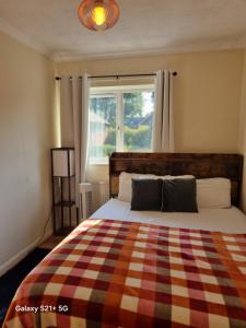 a bedroom with a bed with a checkered blanket and a window at CosyColeby in Nottingham