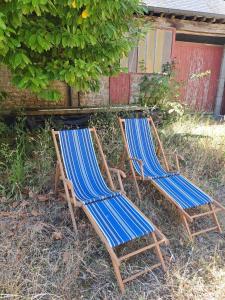two chairs sitting in the grass next to a building at La Ferme de Tréfumel in Tréfumel