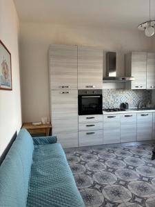 a kitchen with white cabinets and a blue couch at Terrazza delle Acacie in Villaggio San Leonardo