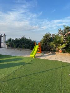 a playground with a yellow slide in a yard at Terrazza delle Acacie in Villaggio San Leonardo