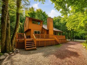 a cabin in the woods with a large deck and a porch at Clocked Out Cabin with Lake Access, Fire Pit, Games in Blakeslee