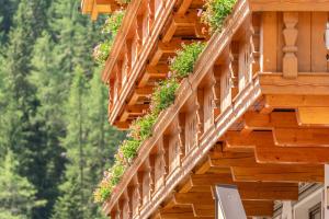 a wooden building with flowers on the balconies at Hotel Schöpf - Mountain Hideaway in Längenfeld