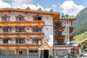 a large white building with wooden balconies on it at Hotel Schöpf - Mountain Hideaway in Längenfeld +95 photos