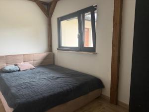 a small bed in a room with a window at Chill and Grill Apartment in Wola Smolana