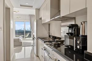 a kitchen with a stove top oven next to a living room at FIRST CLASS Studio Inviting Luxury Escape in Dubai Marina