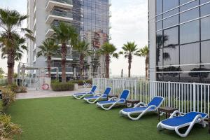 a row of lounge chairs on a lawn with palm trees at FIRST CLASS Studio Inviting Luxury Escape in Dubai Marina