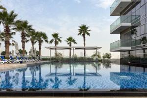 a swimming pool in front of a building with palm trees at FIRST CLASS Studio Inviting Luxury Escape in Dubai Marina