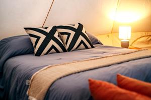 a bed with black and white pillows and a lamp at Glamping Rivera del Mar - RV Park in Loreto