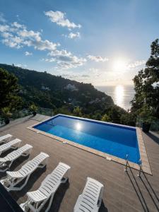 a swimming pool with chairs and a view of the ocean at Villa Deluxe Kvariati in Kvariati