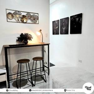 a table and two stools in a room with paintings at Blanc Suite in Roxas City