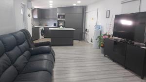 a living room with a black couch and a kitchen at Casa Alentejana in Mora