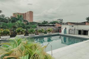 a swimming pool with palm trees and a building at Modern, Fully Equipped and Cozy Loft in Cali