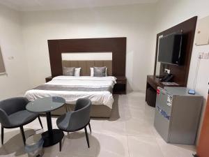 a bedroom with a bed and a tv and chairs at سرور للشقق المخدومة in Al Baha +13 photos