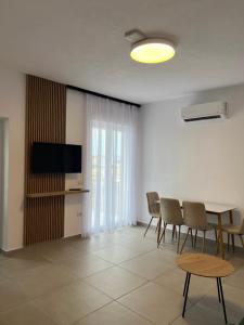 a living room with a table and chairs and a television at Velipoja Residences in Velipojë