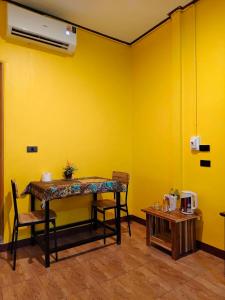 a dining room with a table and a yellow wall at Green Valley Lodge in Khao Sok National Park