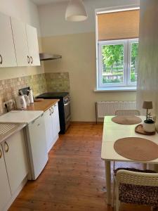 a kitchen with white cabinets and a wooden floor at Baumanis klasika in Valmiera