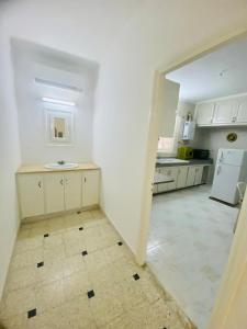 a white kitchen with a counter and a refrigerator at Appart AL MARAII - Familles seulement in Beni Khiar