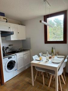 a kitchen with a table and a washing machine at Appartement 2 pièces La Colmiane in La Colmiane
