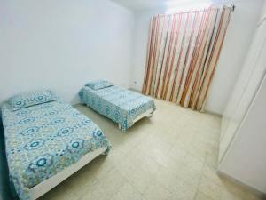a bedroom with two beds in a room with a window at Appart AL MARAII - Familles seulement in Beni Khiar