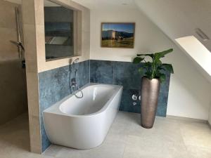 a white bath tub in a bathroom with a potted plant at Ferienwohnung Unterallgäu in Markt Rettenbach +17 photos